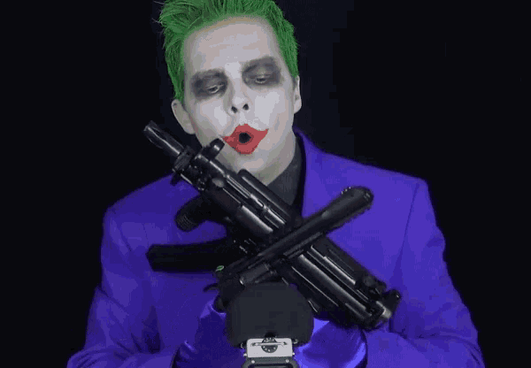 a man dressed as the joker holds a gun in his hand